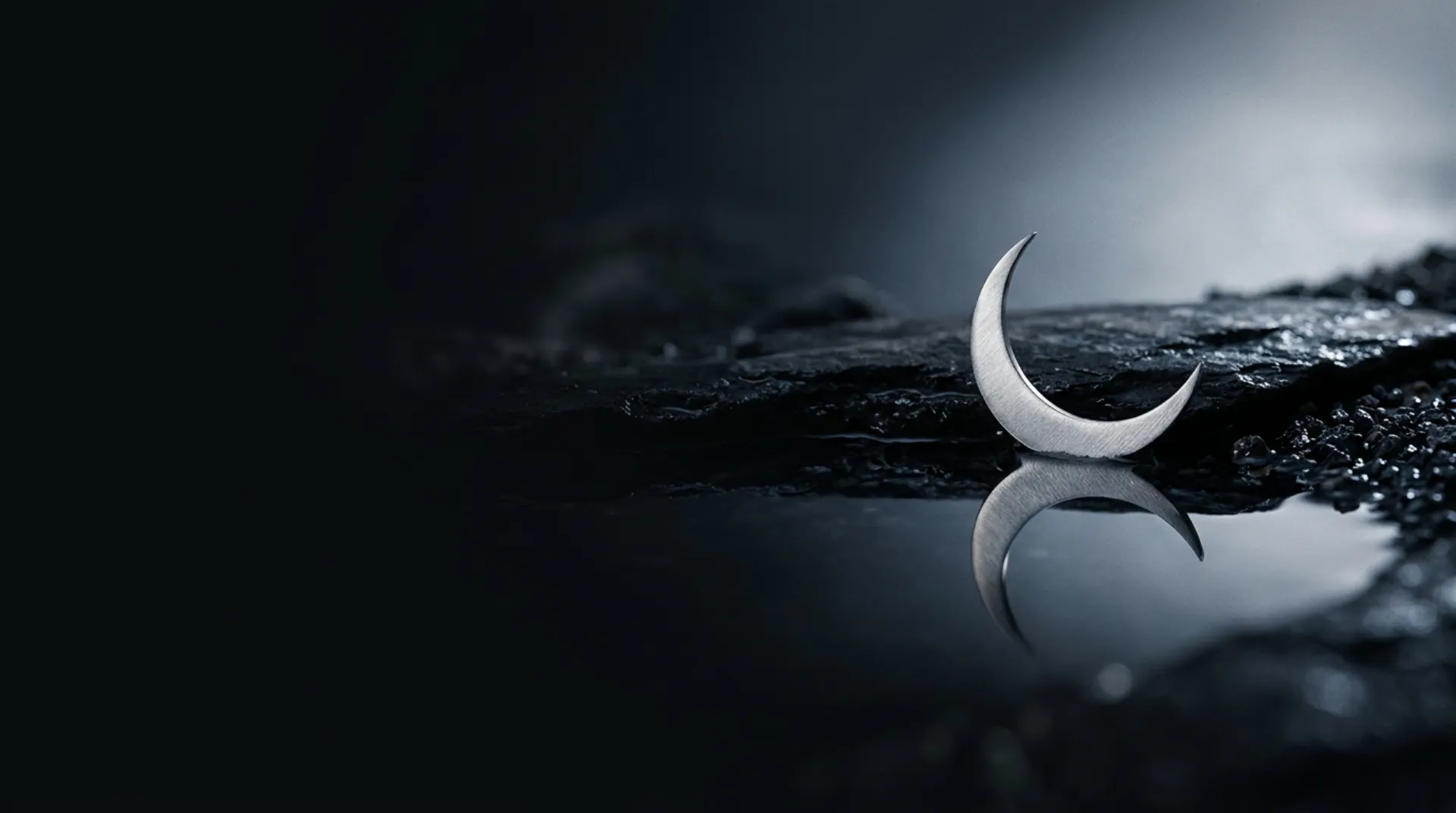 A small brushed-silver crescent reflected in a dark still pool on a dark background, abstract hero artwork for Kimi K2.6